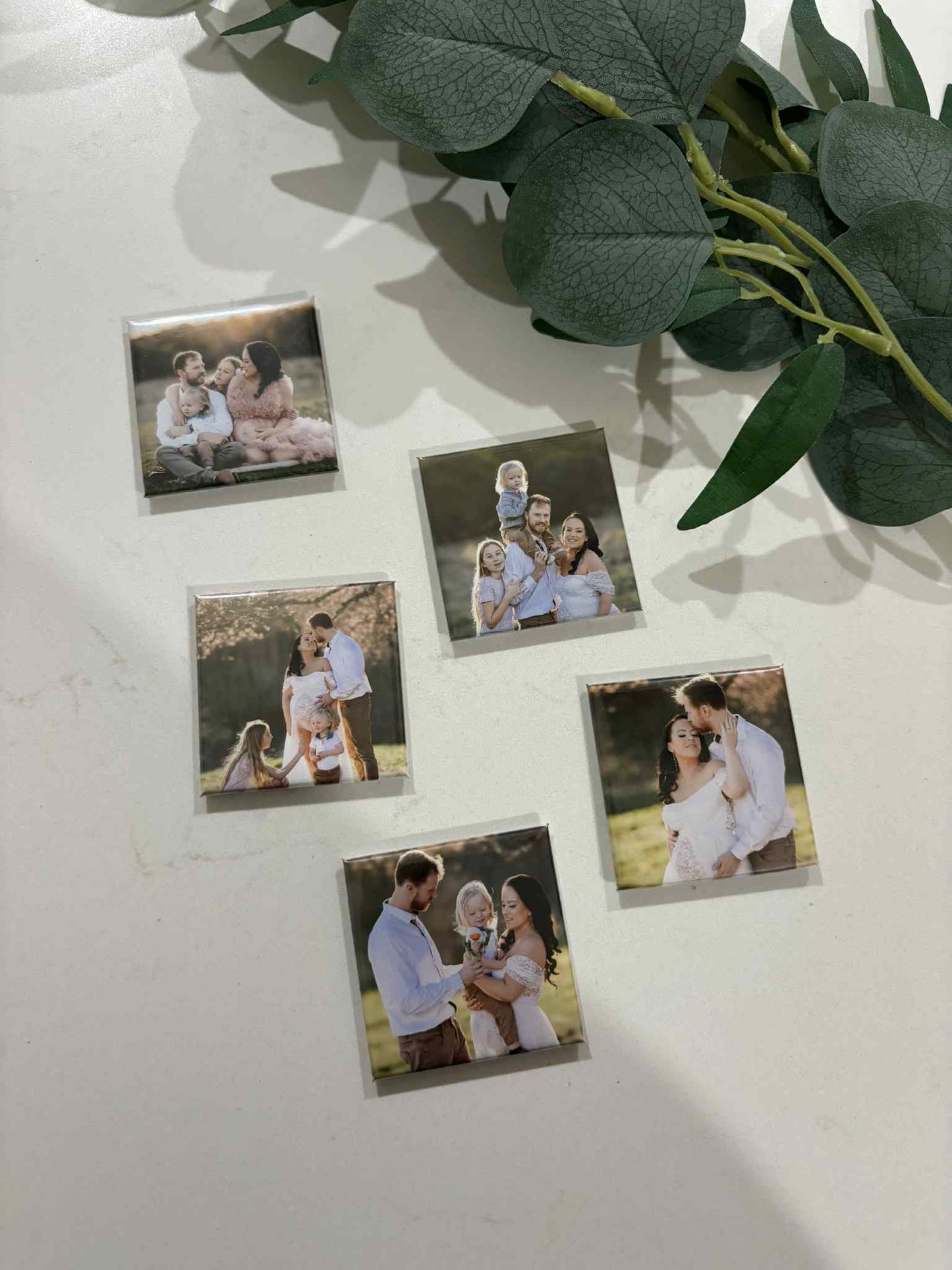 Set of custom family photo magnets displayed on a white surface with greenery — ideal for family keepsakes or gifts.