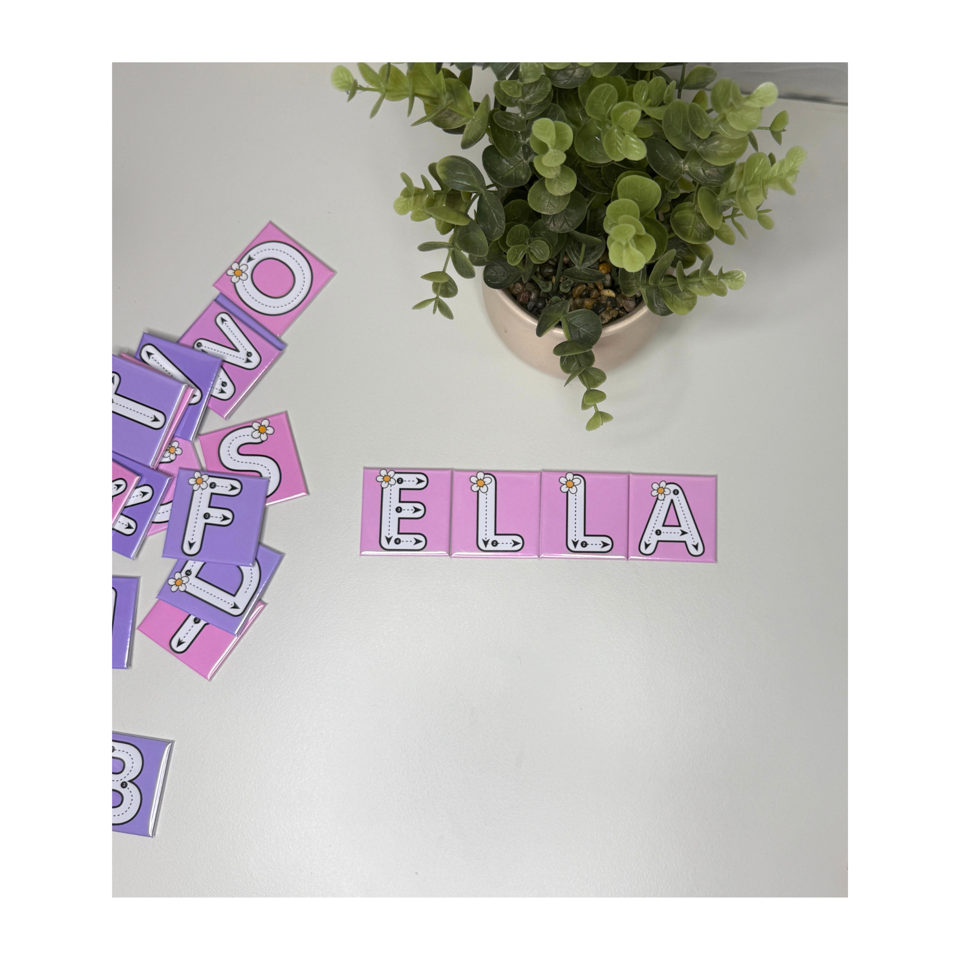 A set of four custom name tracing magnets spelling ELLA. The magnets are pink with dashed tracing lines and a white flower illustration for early learning and name recognition.