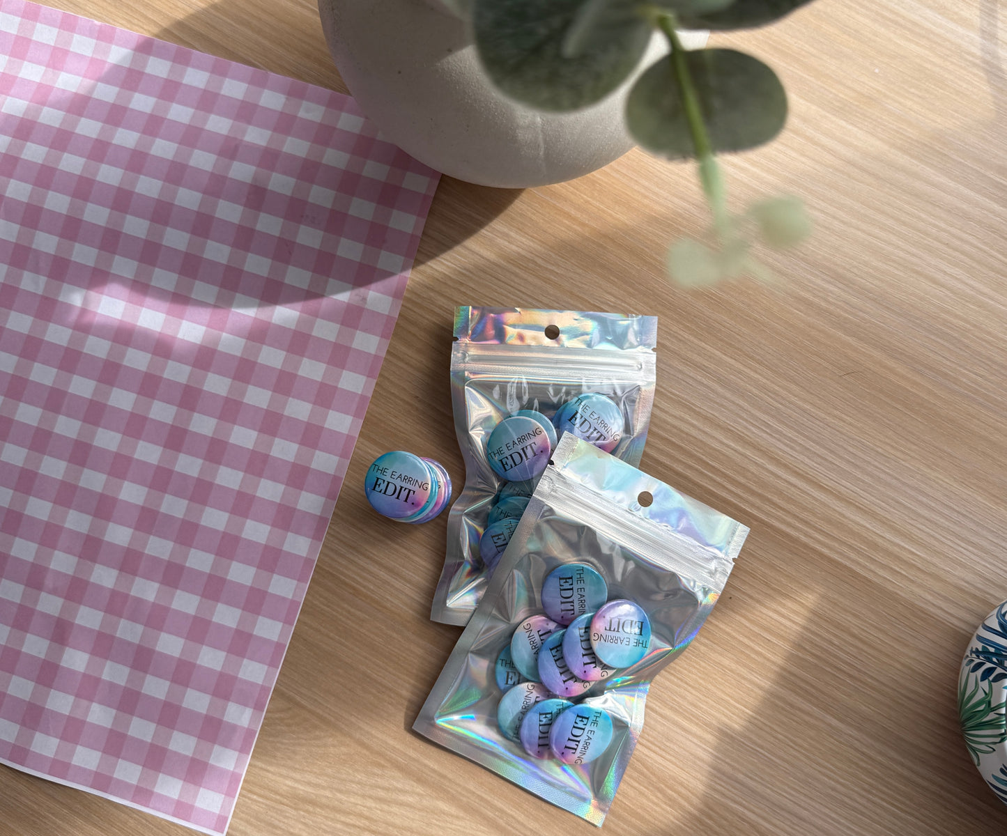 A stack of packaged custom logo magnets sitting in front of a purple gingham background prop.