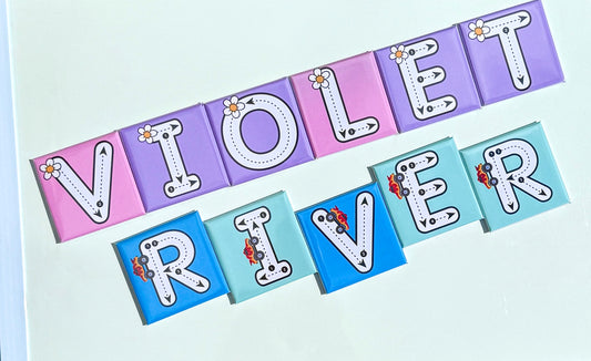 Colorful paper letters spelling 'VIOLET RIVER' on a light blue background