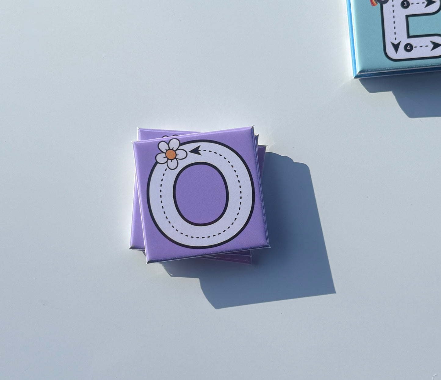 Purple letter 'O' box with a flower on a light gray background